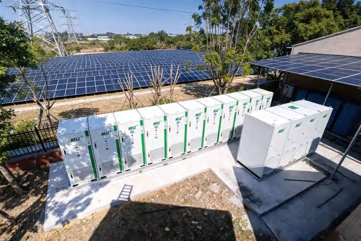 Long row of HELZ battery cabinets under a large rooftop PV array at a car accessories factory